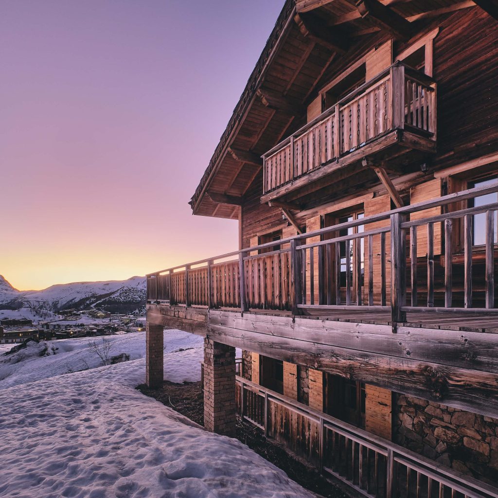 A long shot of the facade of a cabin in Alpe d Huez ski resort in the French Alps during sunrise